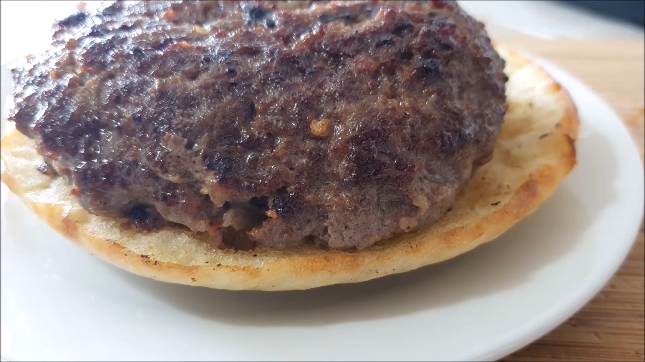 Pečena domaća pljeskavica servirana u lepinji na tanjiru