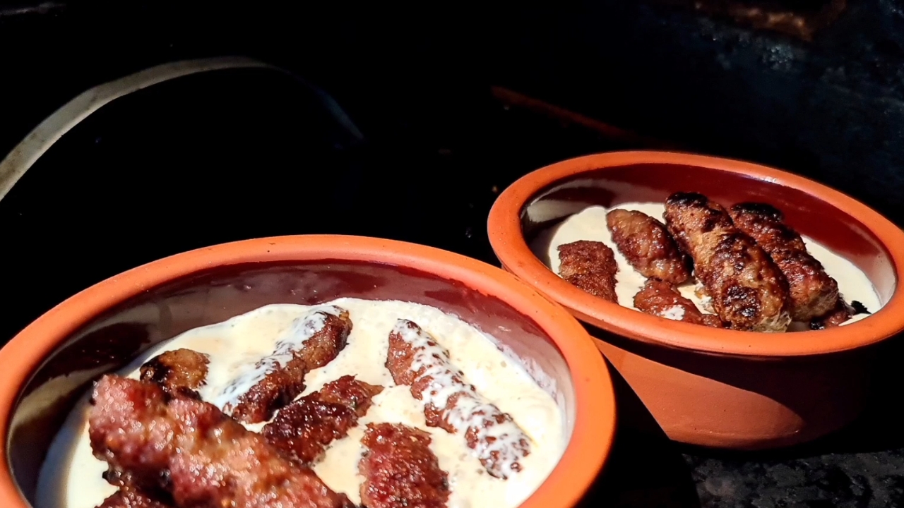 Ćevapi sa kremastim kajmakom posluženi u zemljanim posudama